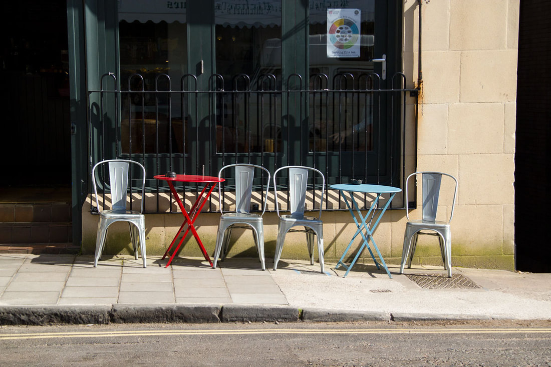 Chairs sits right outside of the coffee shop on the pavement 