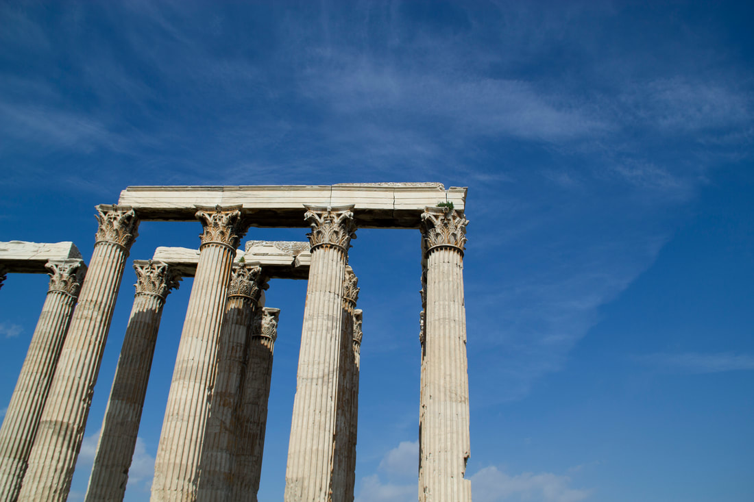 Pillars of ancient Greek ruin standing in front of the blue sky