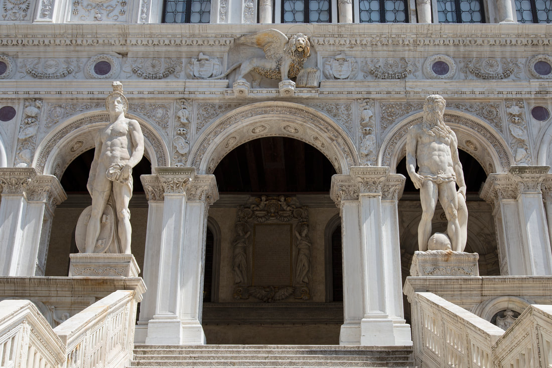 White building with exquisite carving exterior and two statues on top of the stairs