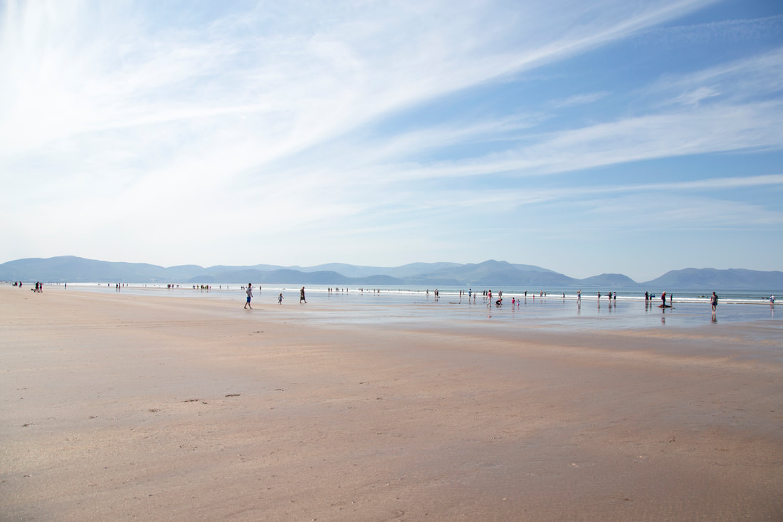 People on the beach with blue sky and mountains in the back