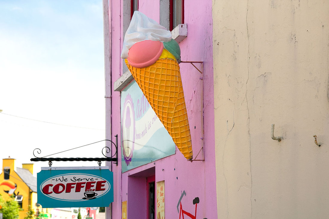 A giant ice cream sign outside of a coffee shop on a pink wall