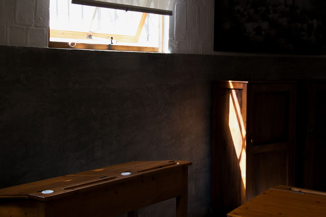 A class room with wooden tables and cupboard with sun coming from the window