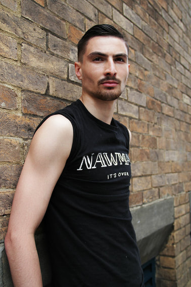 Male model in black shirt standing against on the brick wall besides to the street of London 