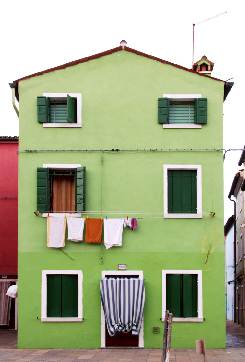 A bright green fisherman house with rich green colour windows sits on the street of Burano. 