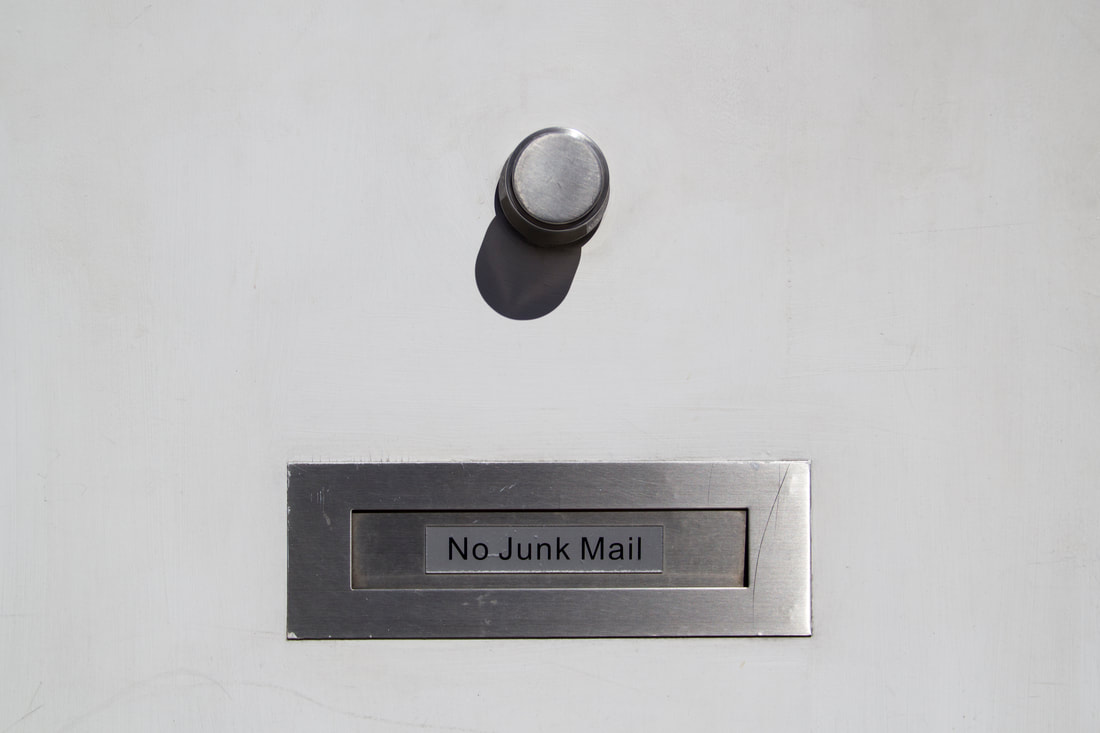 A white door with silver handle and mailbox with stickers written 