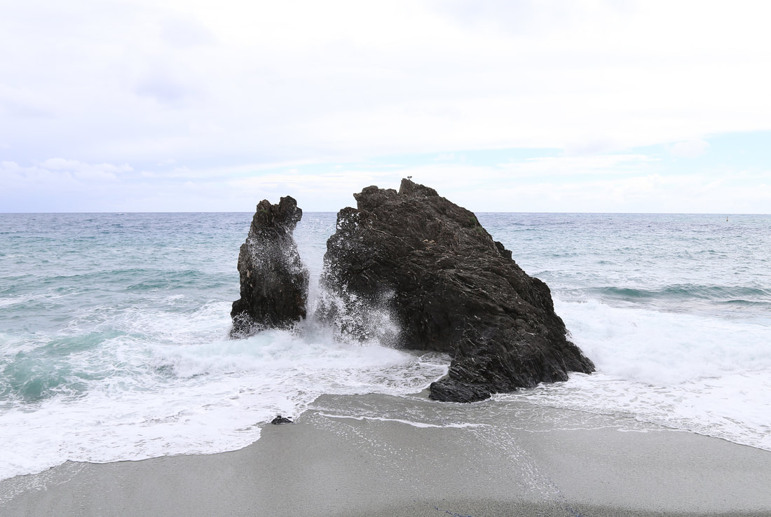 A wave splashes through the rocks on the beach. 