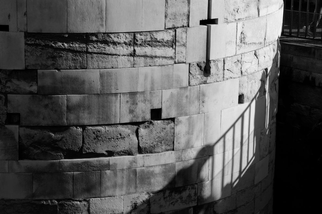 The shadow of people and railing on the wall of the tower of London.