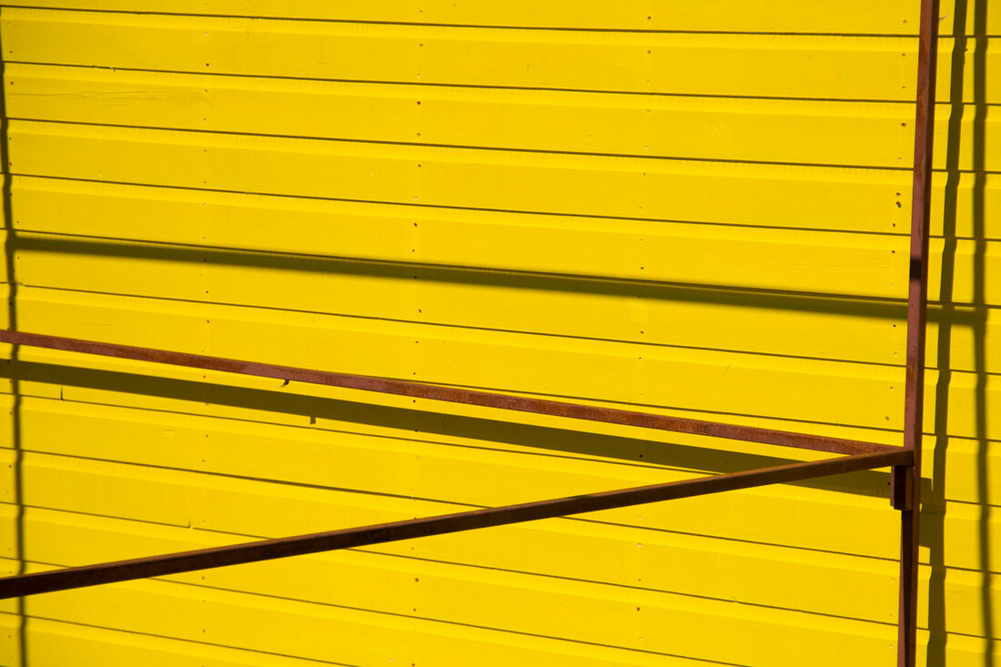  Rusty stands in front of a bright yellow rolling steel door and creates lines of shadows on it. 