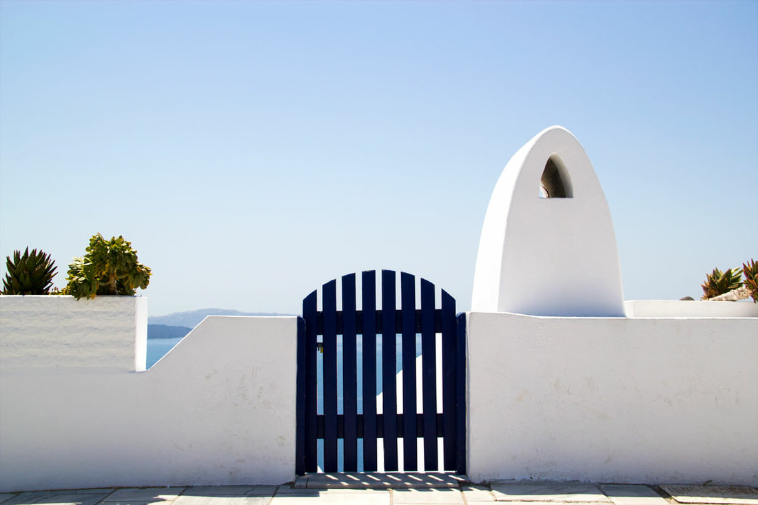 White short wall and a little blue fence door in Oia, Santorini. 
