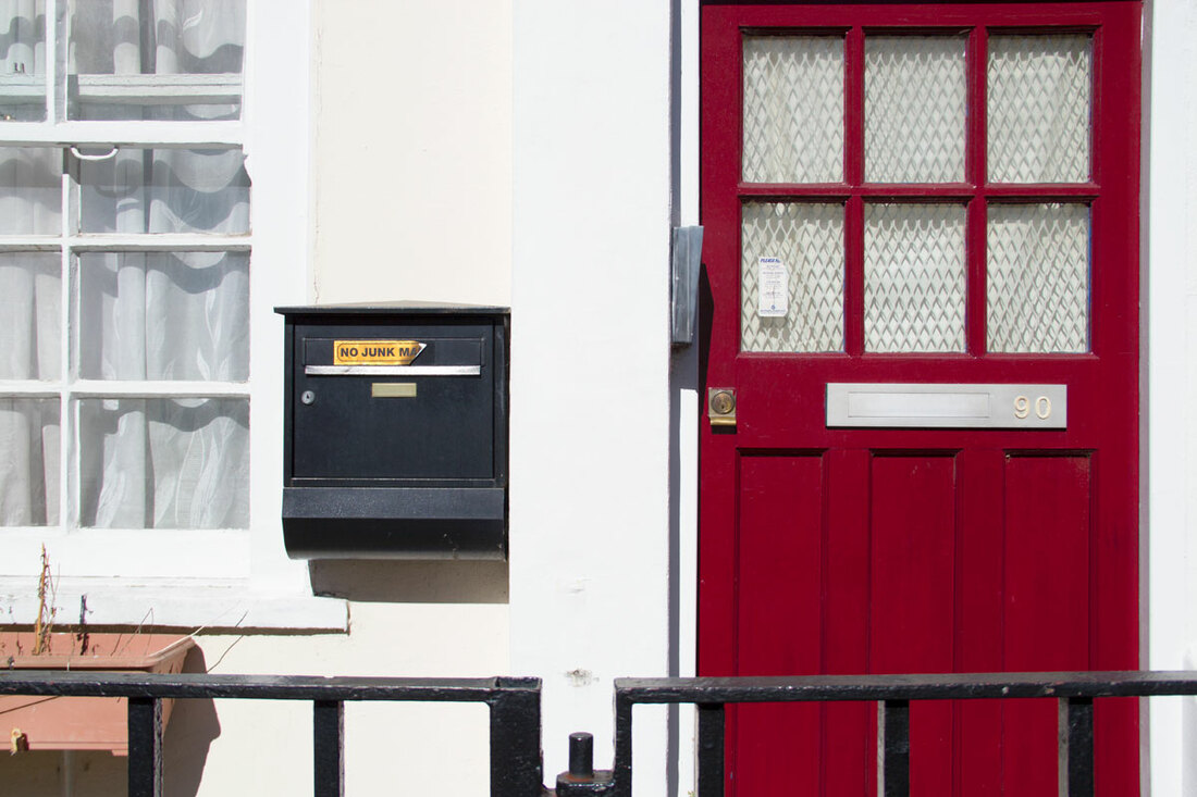 A house with a black mailbox and a red door in Notting Hill, London 